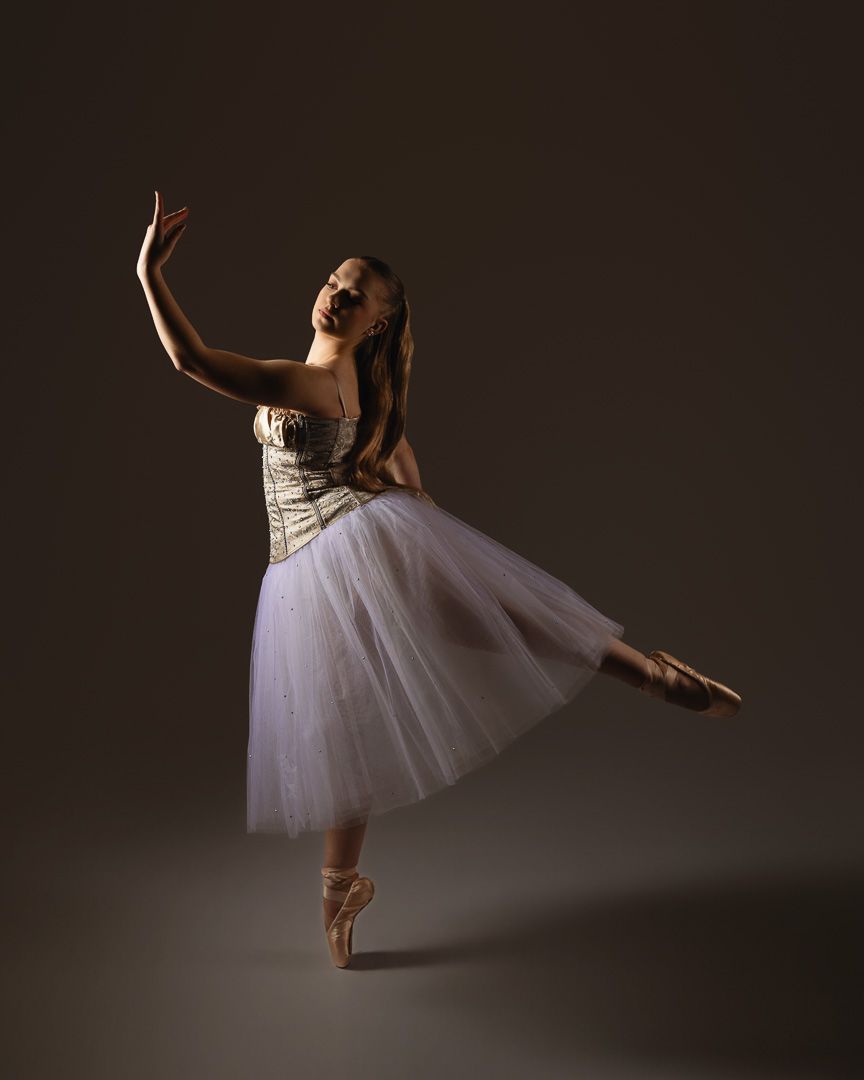 Graceful ballet dancer in white tulle dress performs elegant poses against dark background in artistic photo series.