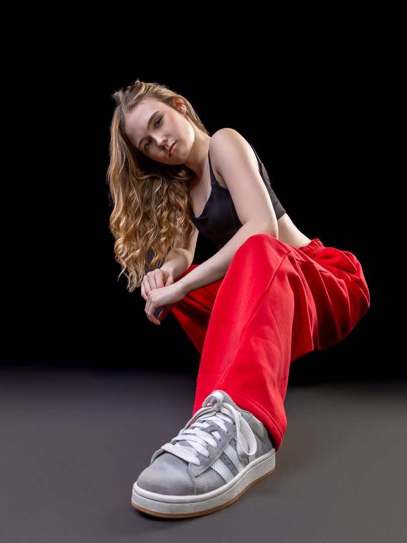 Dynamic dance poses in red outfit with gray sneakers against dark backdrop.