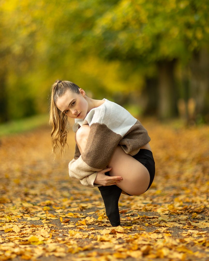 Graceful dance poses captured in autumn leaves with warm golden lighting.