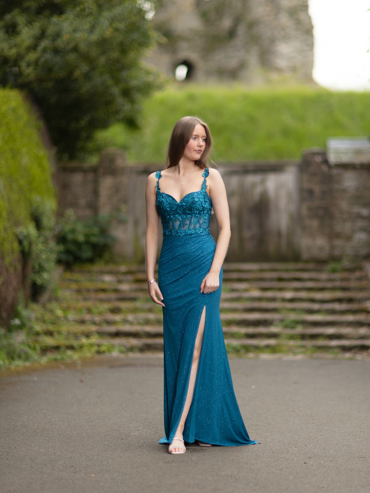 Flowing teal dress with high slit captured in outdoor photoshoot on stone steps.