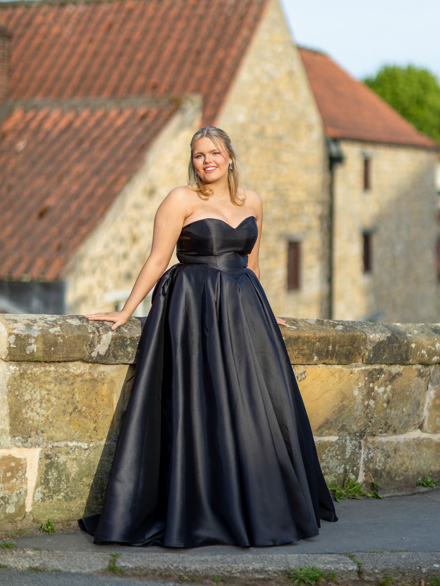 A black formal gown stands out against stone buildings and architecture.