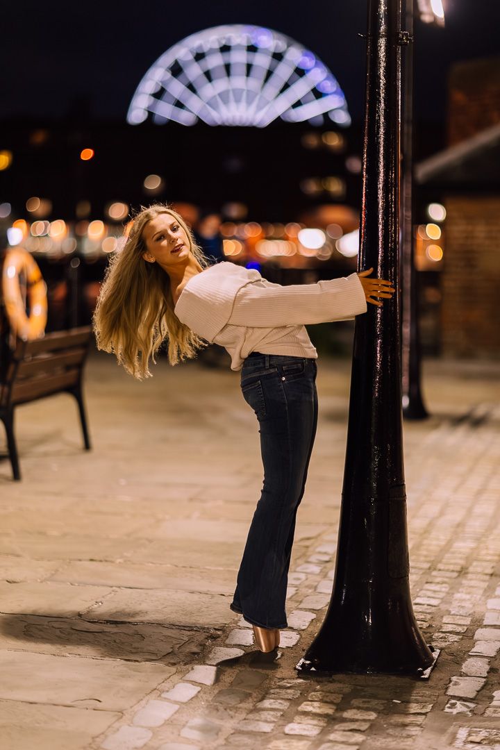 Artistic dance poses against a lamp post at night with bokeh lighting effects.