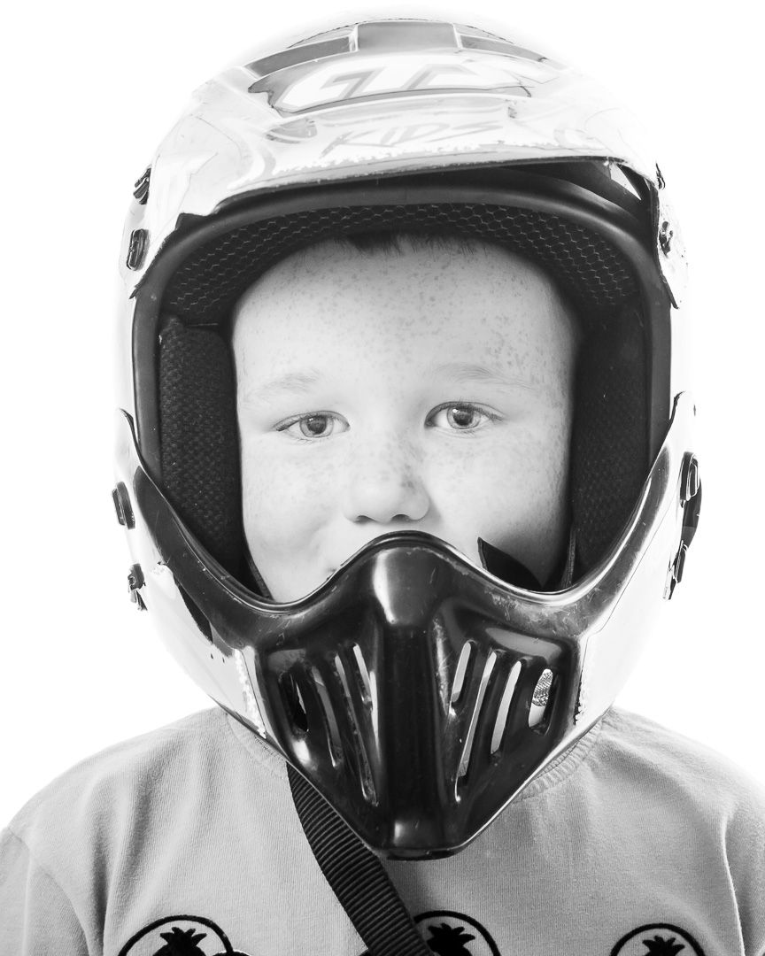 Three people wearing black protective motorcycle helmets and goggles in a black and white photograph.
