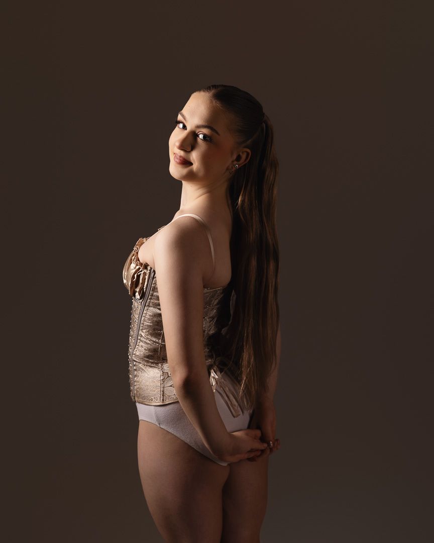 Artistic portrait in muted lighting showcasing dance attire and graceful pose.