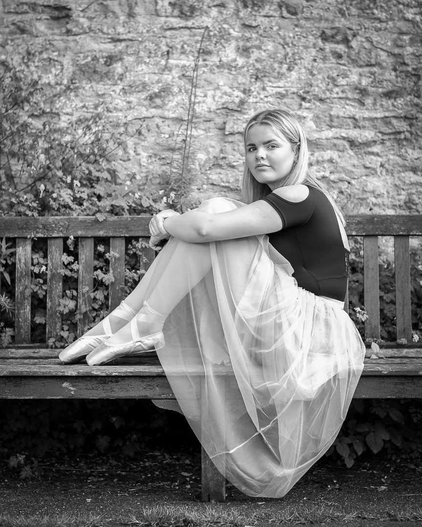 Artistic black and white portraits of dancer in flowing white dress on bench.