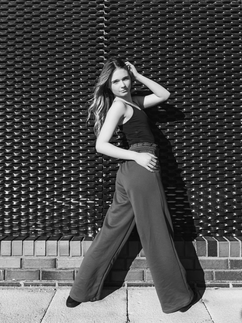 Modern dancer performs contemporary moves against textured black wall.