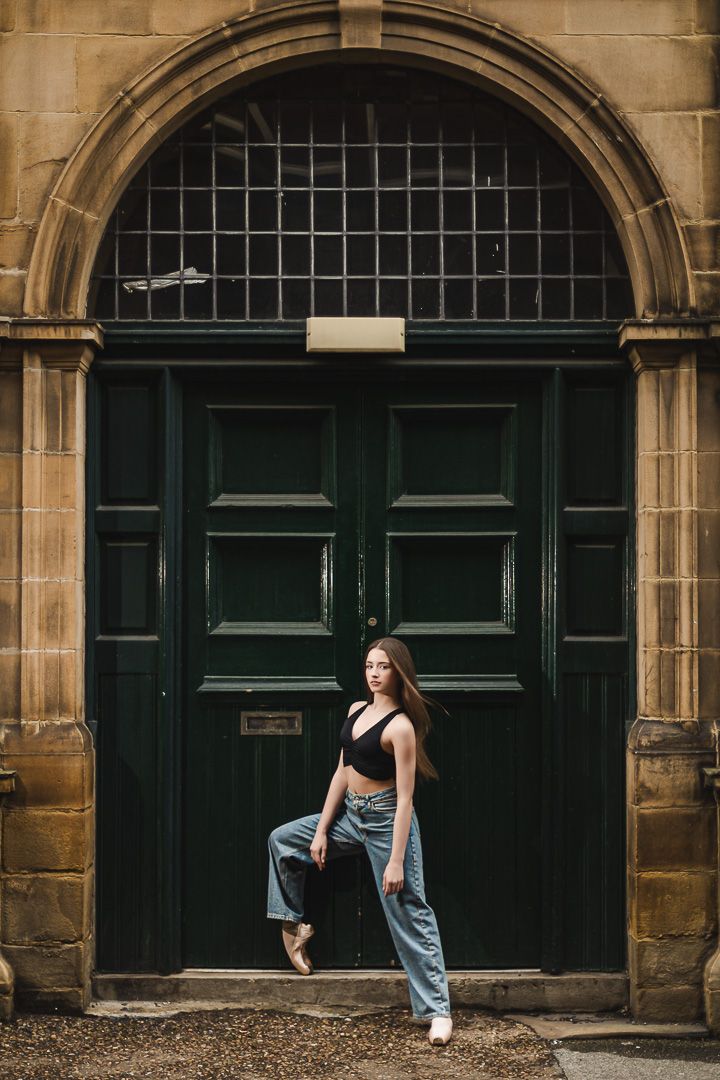 Dance sequence against historic stone building with dark green doors and arched architecture.
