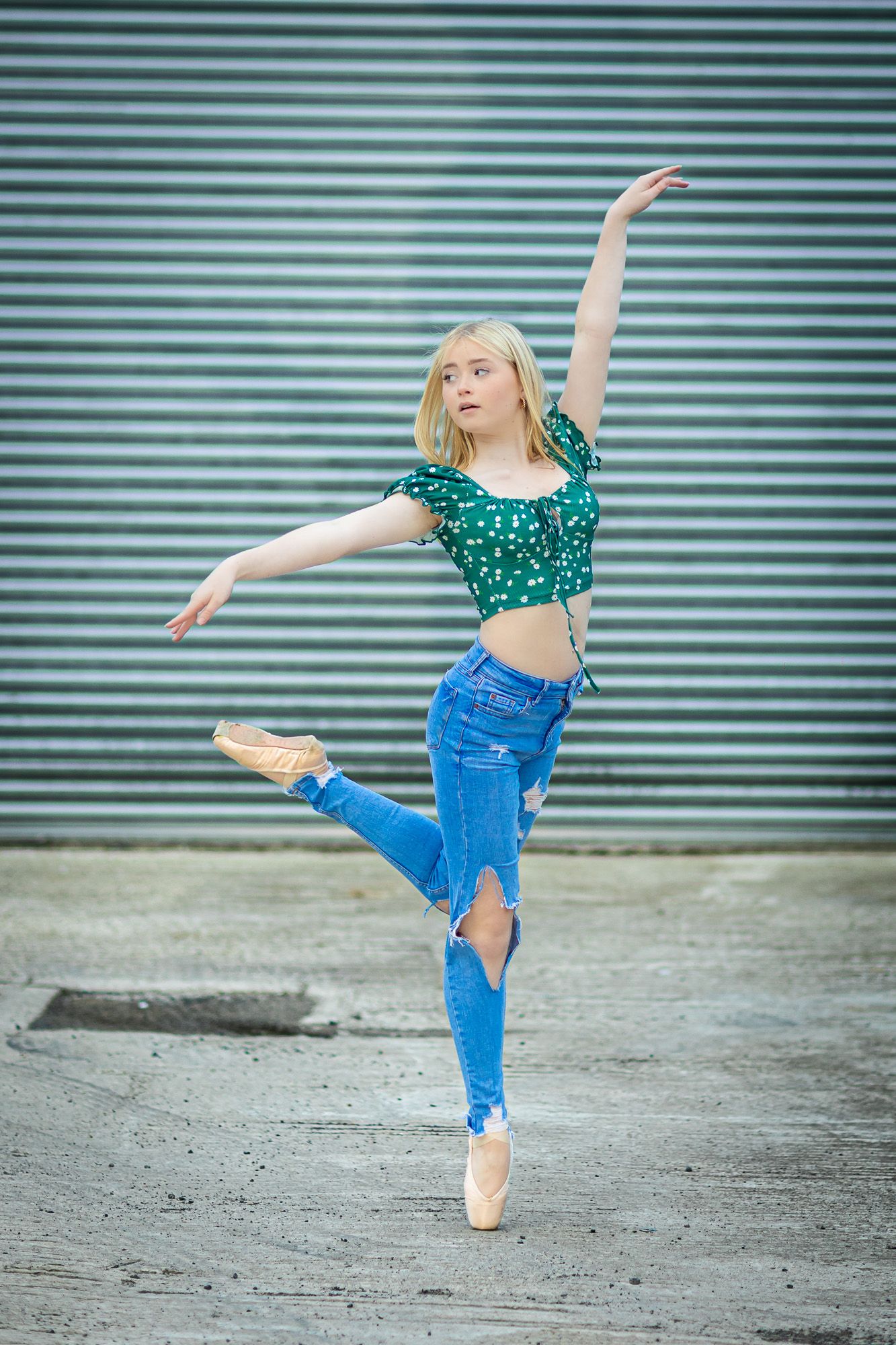 Dancer in green top and jeans performs dynamic poses against industrial metal backdrop.