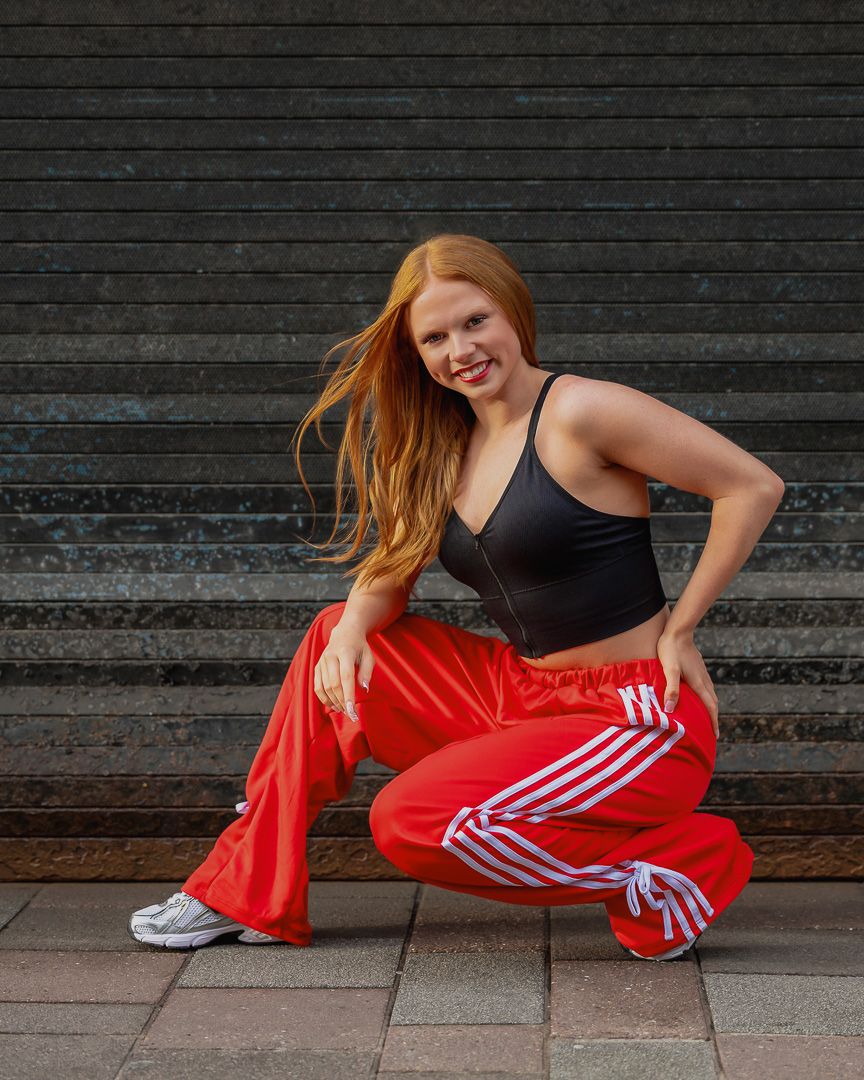 A sequence of dance movements showing a person in red pants performing dynamic stretches against a dark wall.