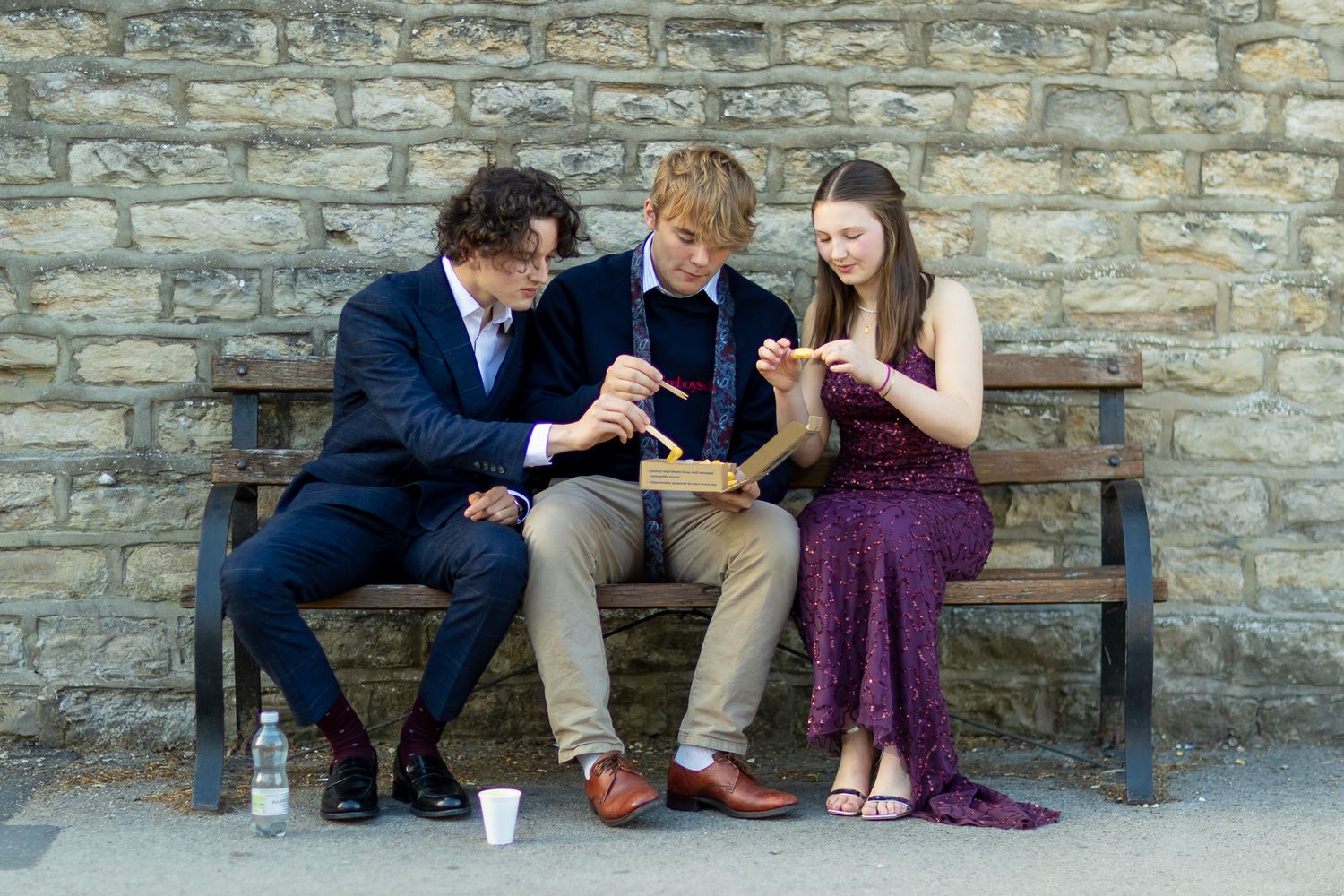 Group sitting casually on stone bench during formal photo session.
