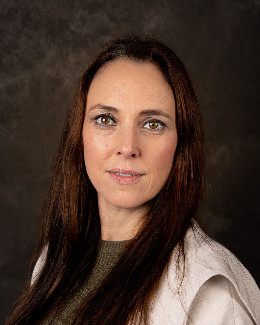 Professional headshot of person in white and olive attire against dark backdrop.