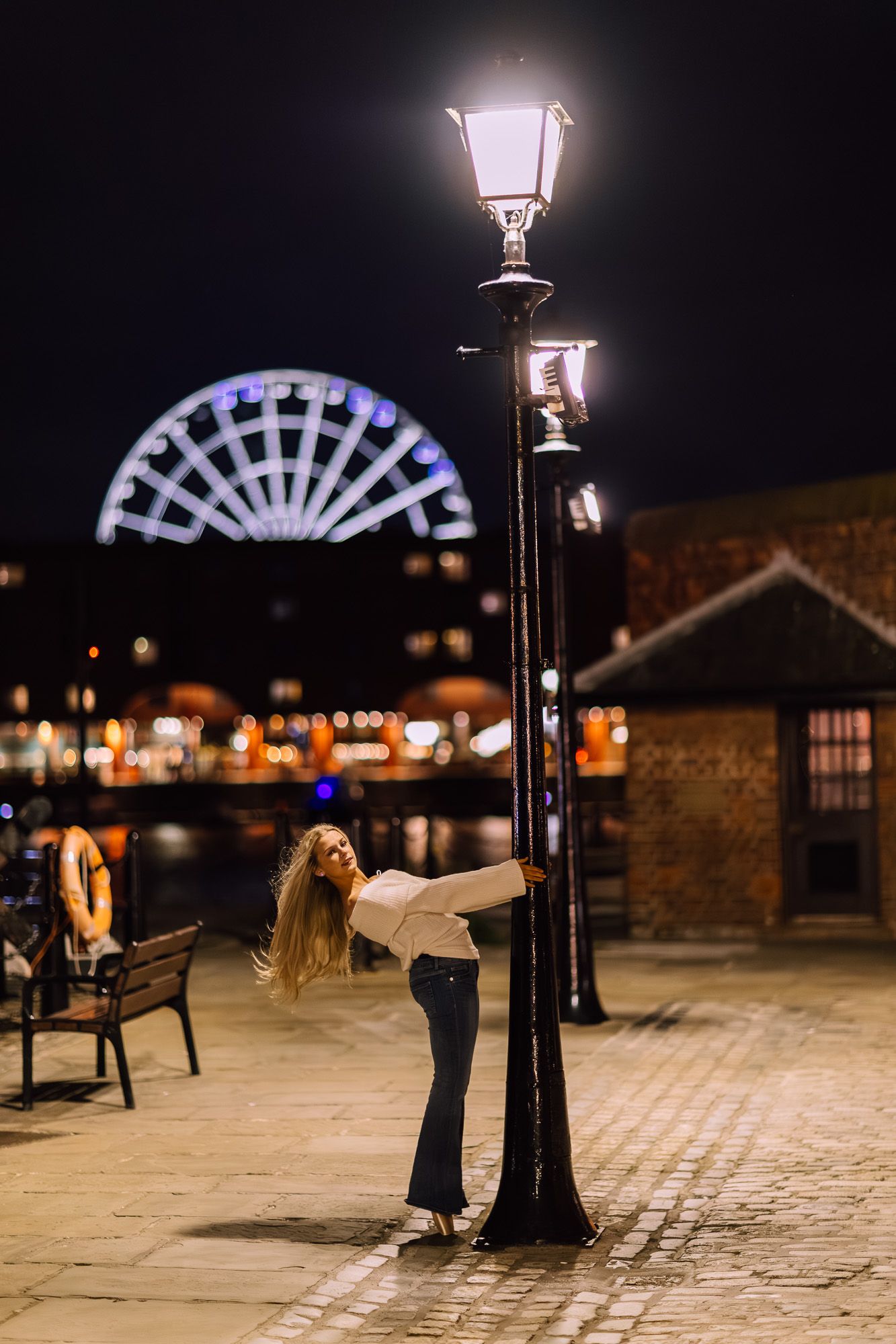 A sequence of artistic dance movements captured at night under vintage street lamps in a cobblestone plaza.