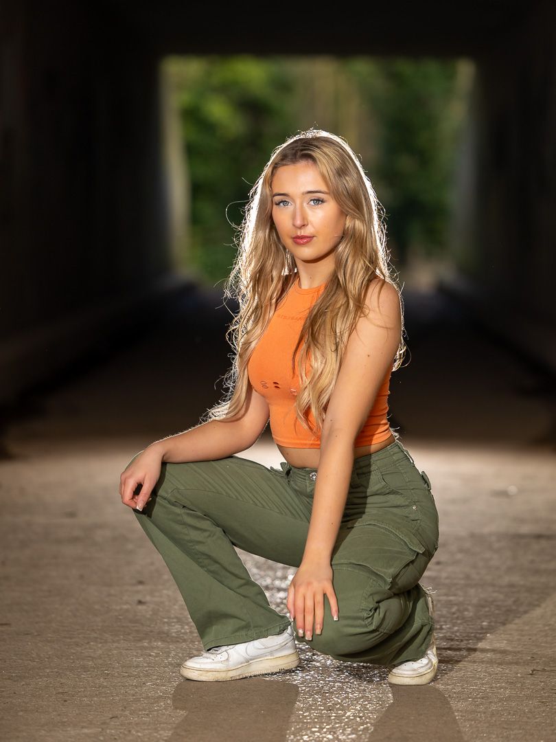 Casual outdoor portraits in orange top and olive pants with natural lighting.