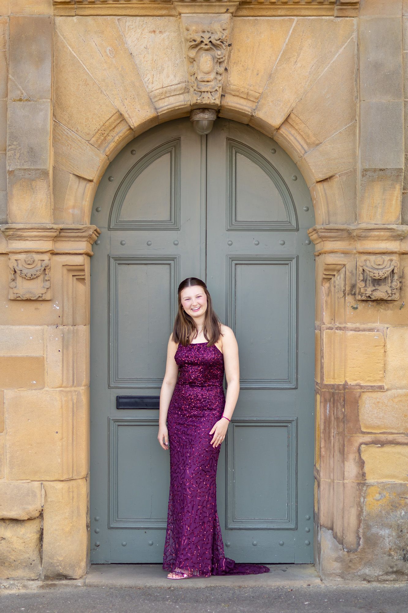 Elegant photo shoot against stone building with blue-gray doors and architectural details.