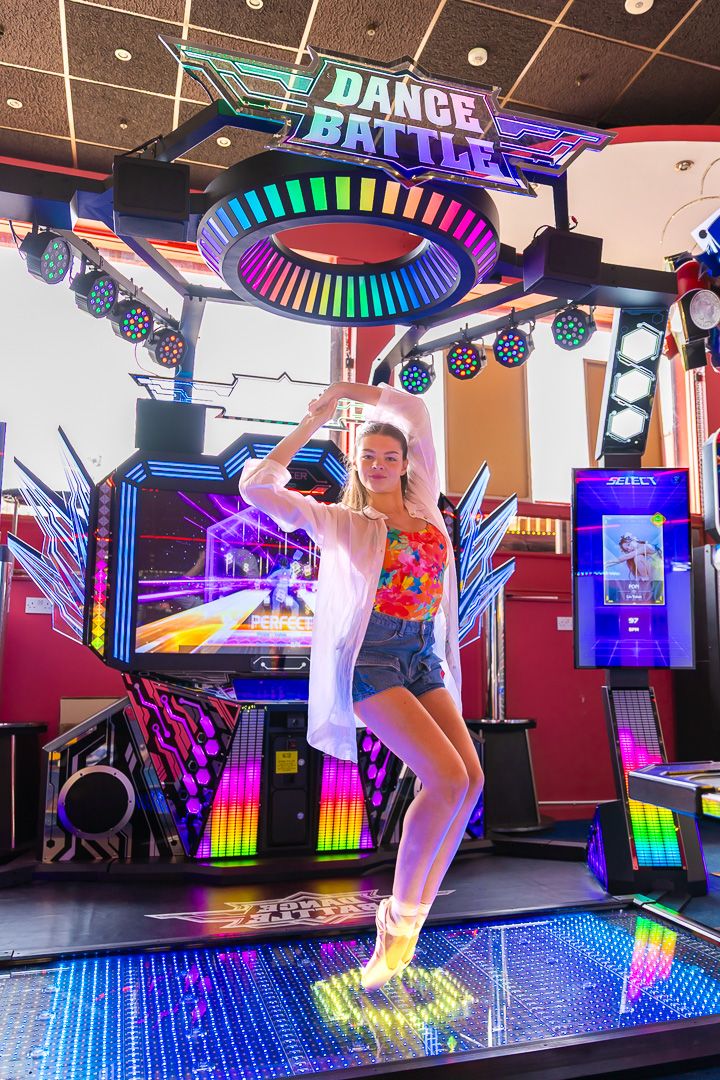 Dance studio with colorful neon lights and illuminated floor showing dynamic dance movements.