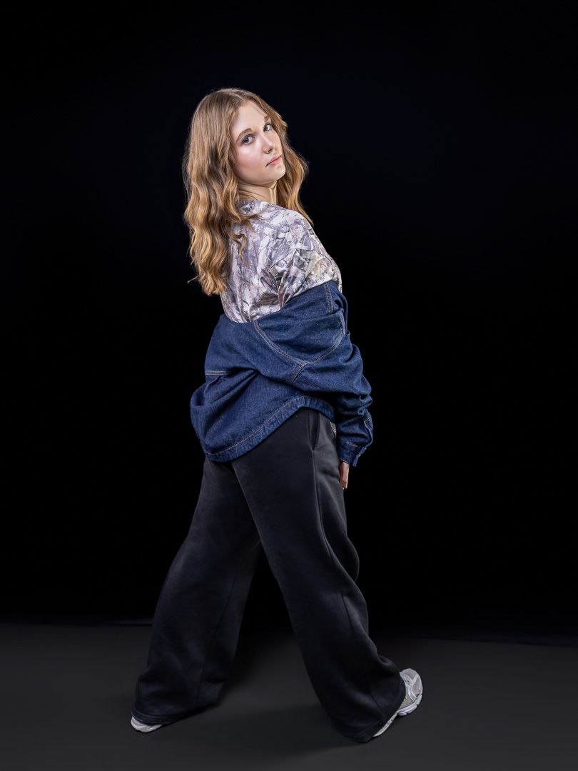 Dance sequence showing movement in oversized navy hoodie against black background.
