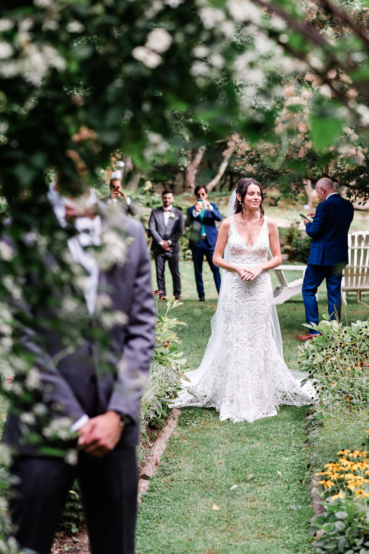 An image of a bride during her first look ceremony, surrounded by greenery.