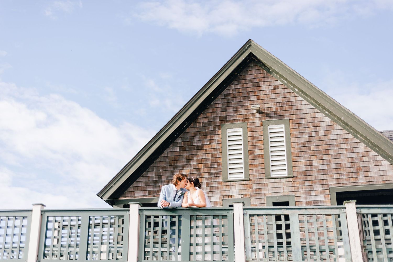 a bride and groom in front of a beach house