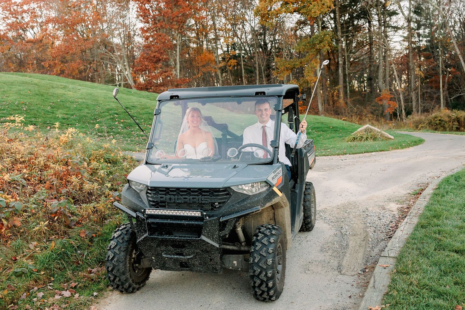 A bride and groom celebrating their wedding on a golf course in a golf cart.