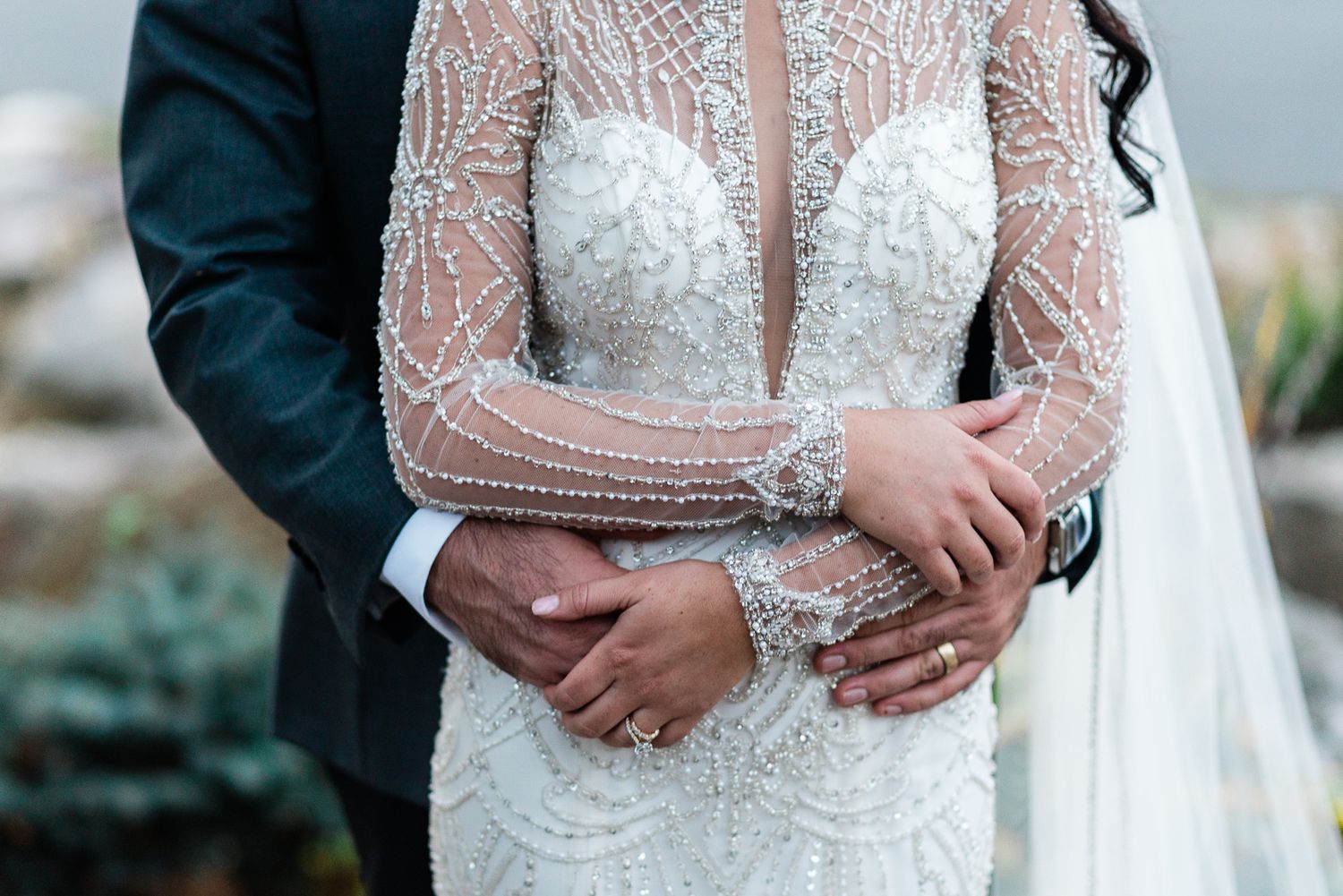 A close up detail shot of a bride and groom holding each other.