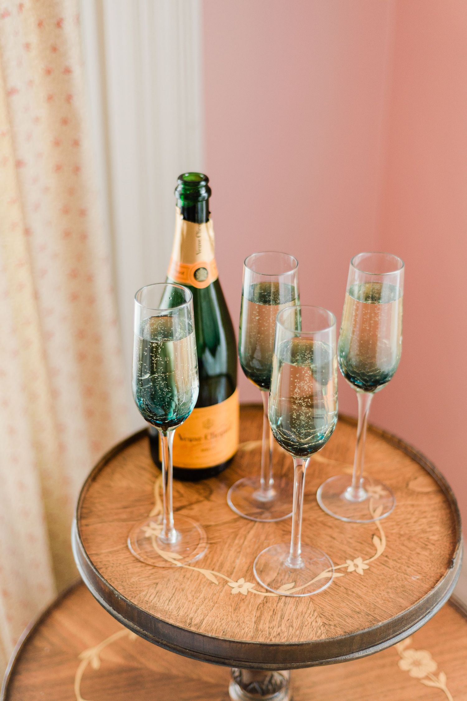 a detail shot of champagne and glasses in a vibrant  pink room