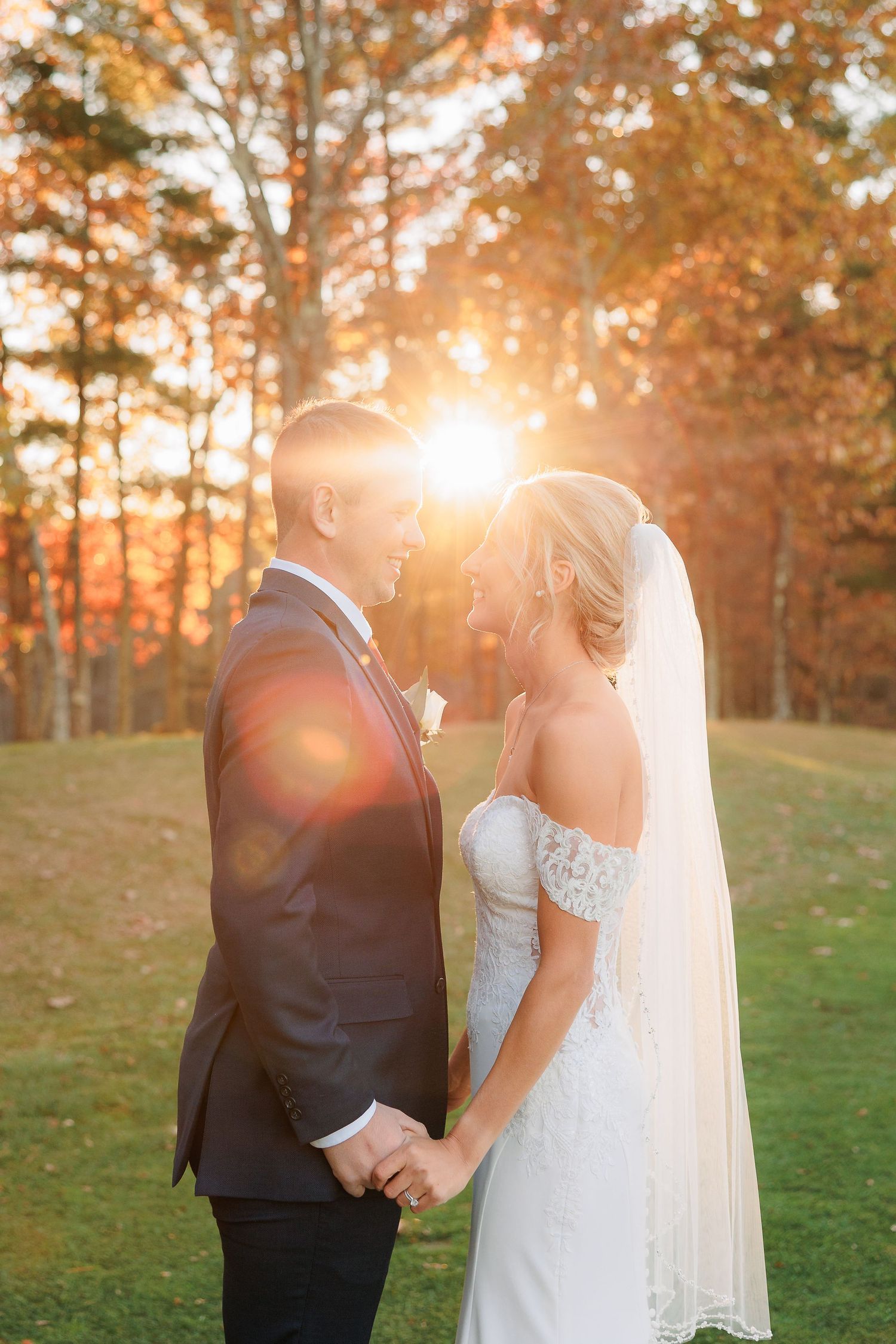 a bride and groom face each other and smile with the camera catching the sunset haze