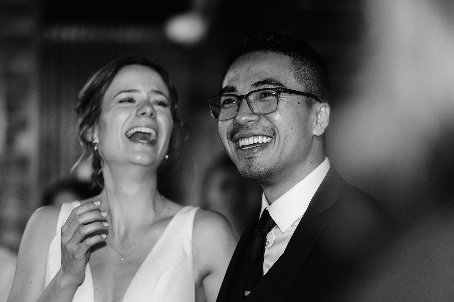 a black and white photo of a bride and groom laughing
