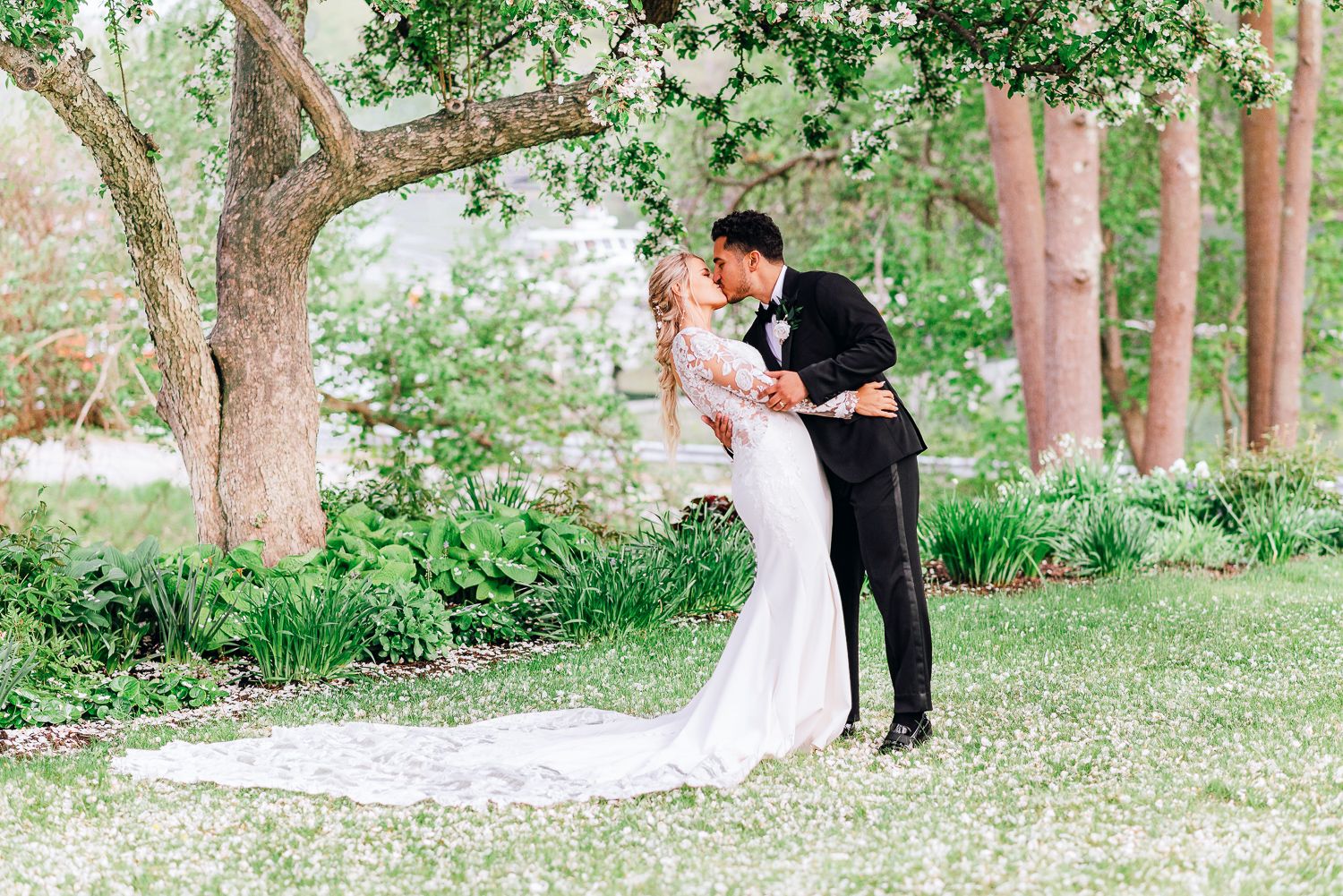 Bride and groom kissing during their wedding photos under cherry blossom trees in Maine.
