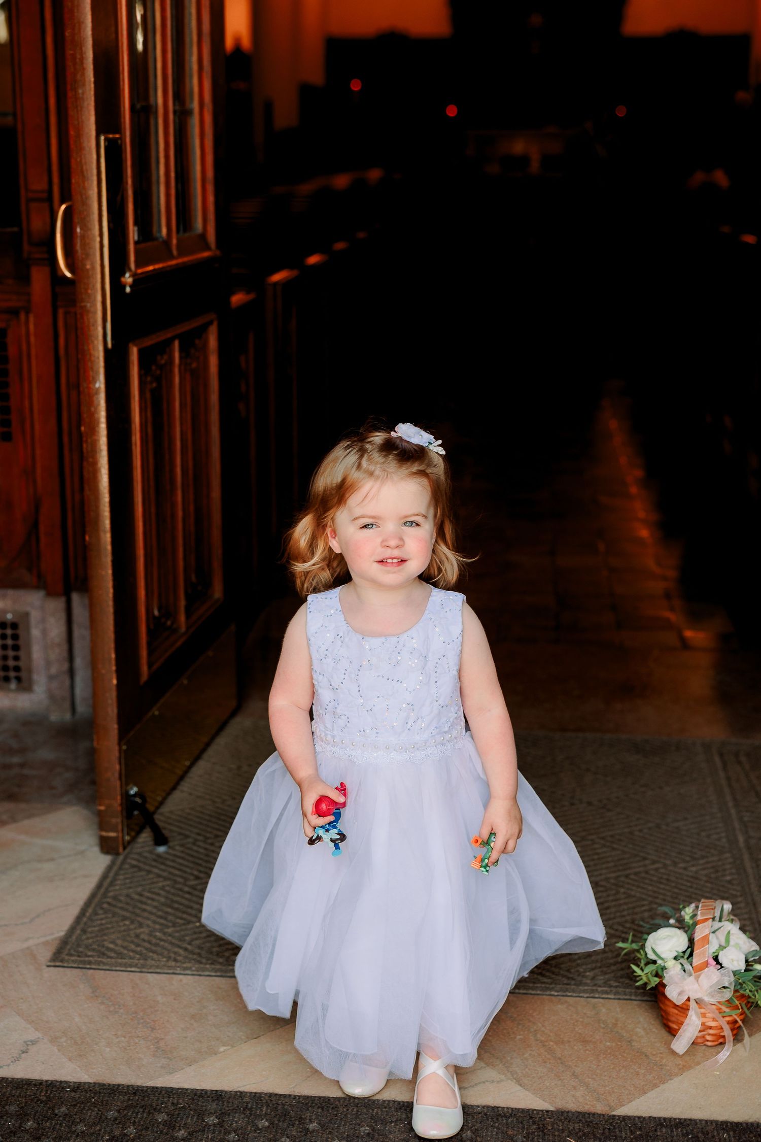 a flower girl poses outside of a church wedding