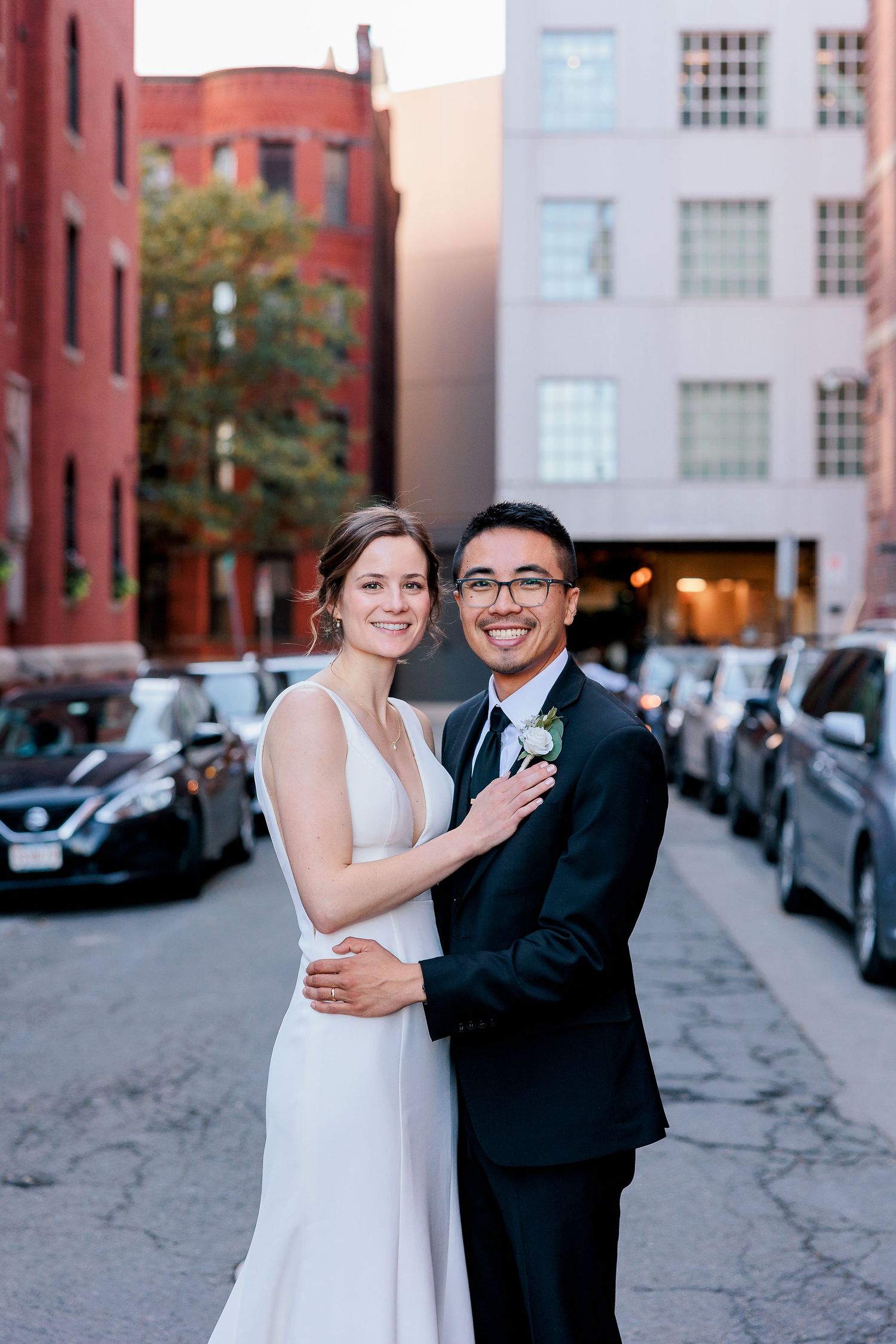 A bride and groom smile in the middle of a city street.