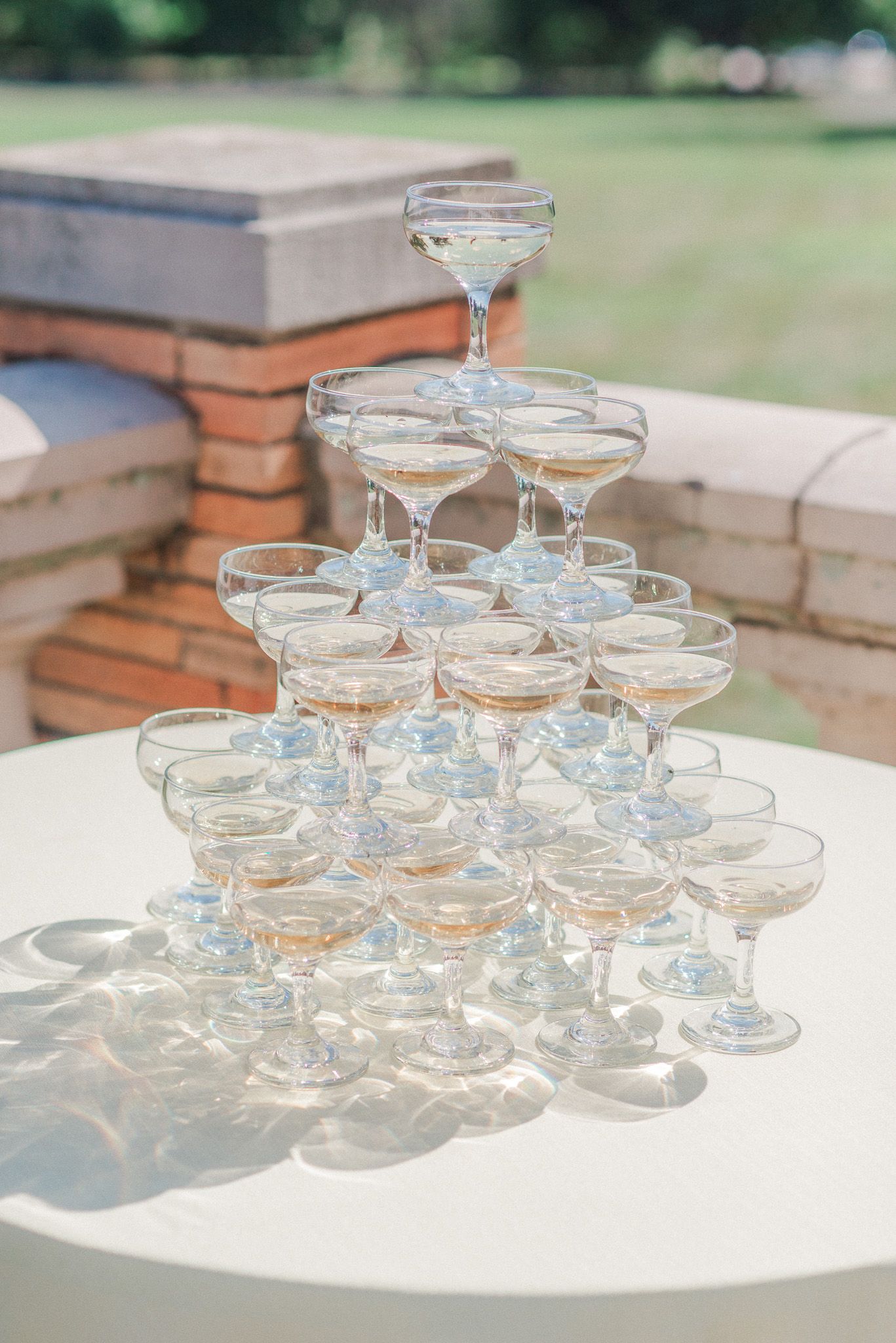 A champagne tower during a sunny wedding reception.