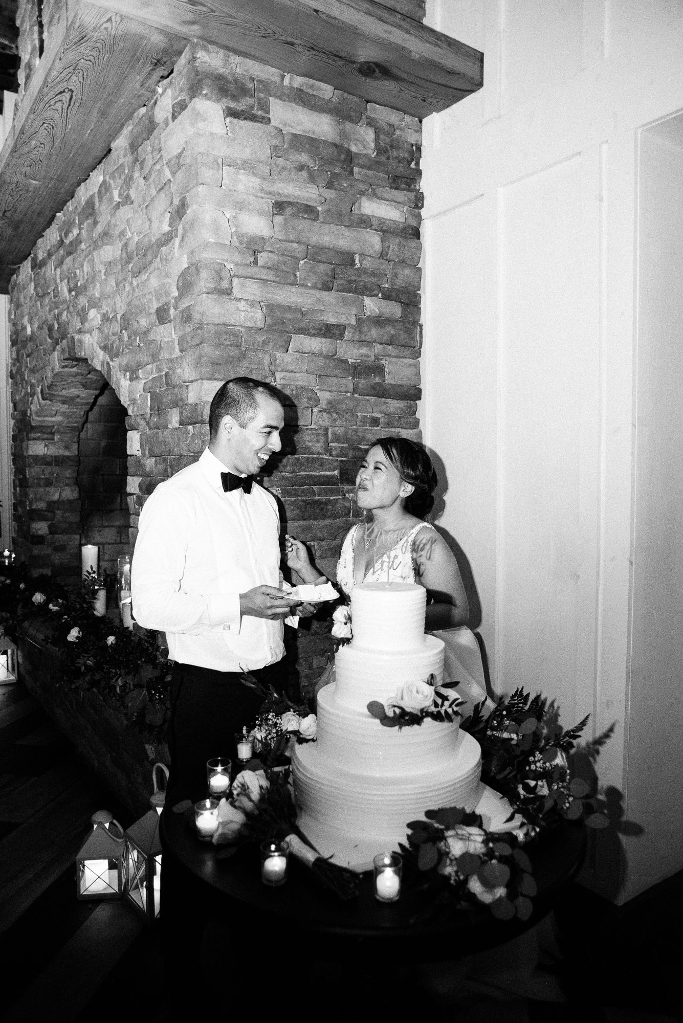 A black and white flash photo of a bride and groom eating wedding cake.