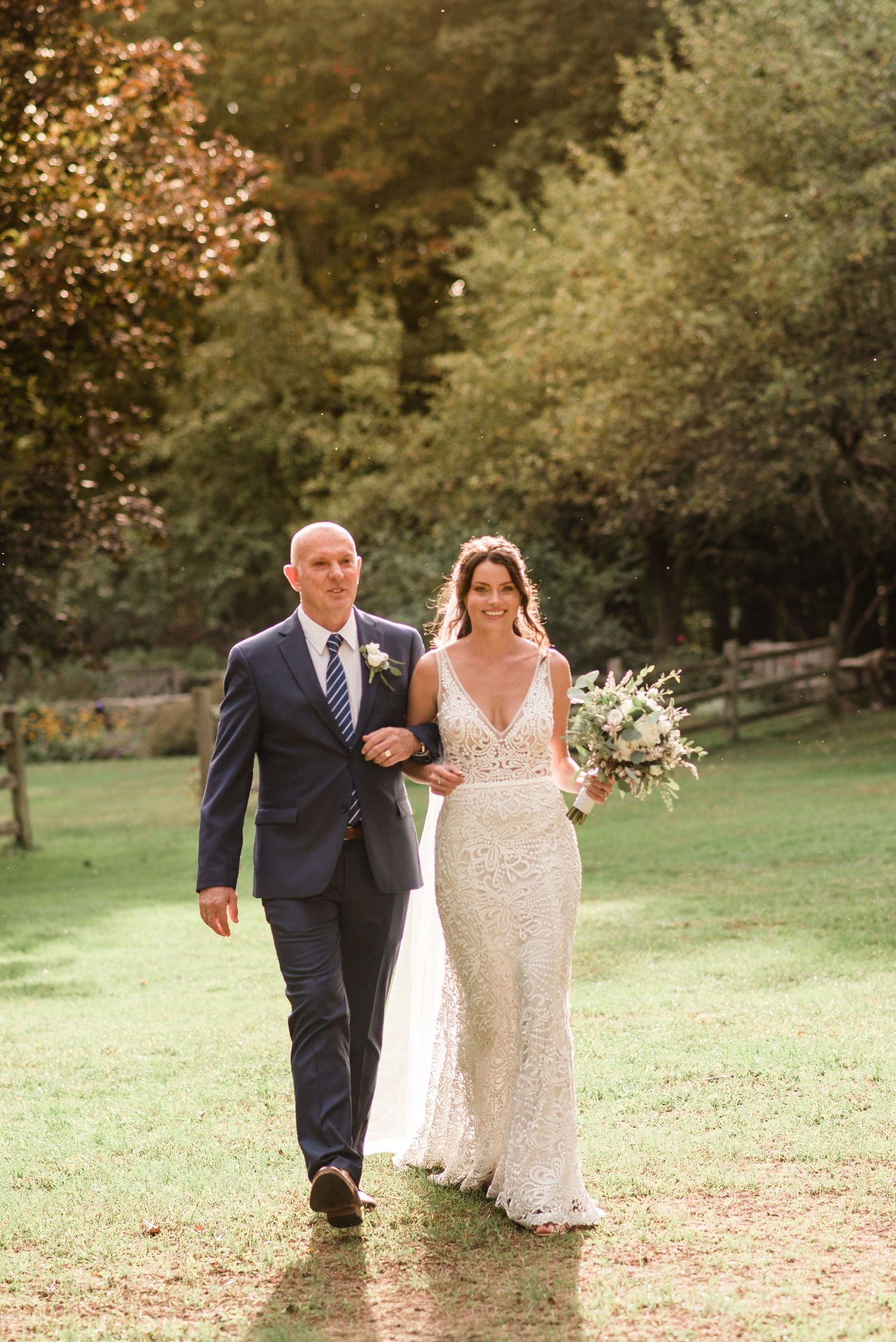 a father walks his daughter down the aisle surrounded by golden hour light