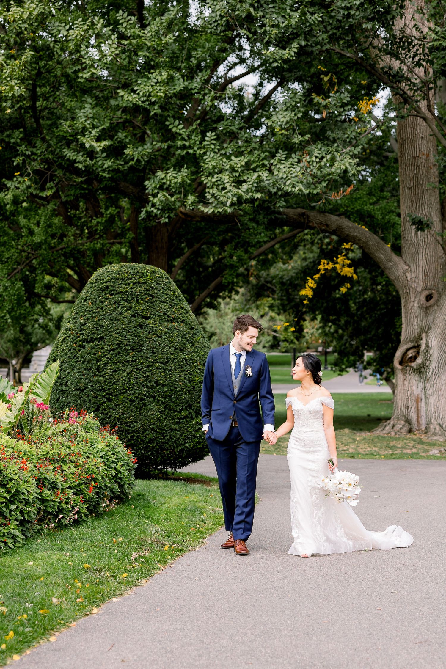 A bride and groom walk through the Boston Common gardens.