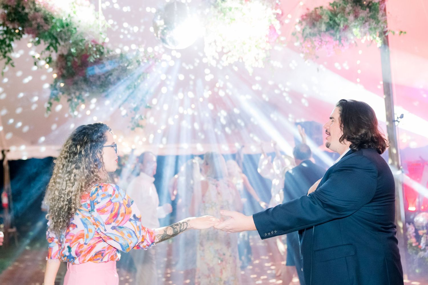 a couple dances underneath disco light at a wedding reception