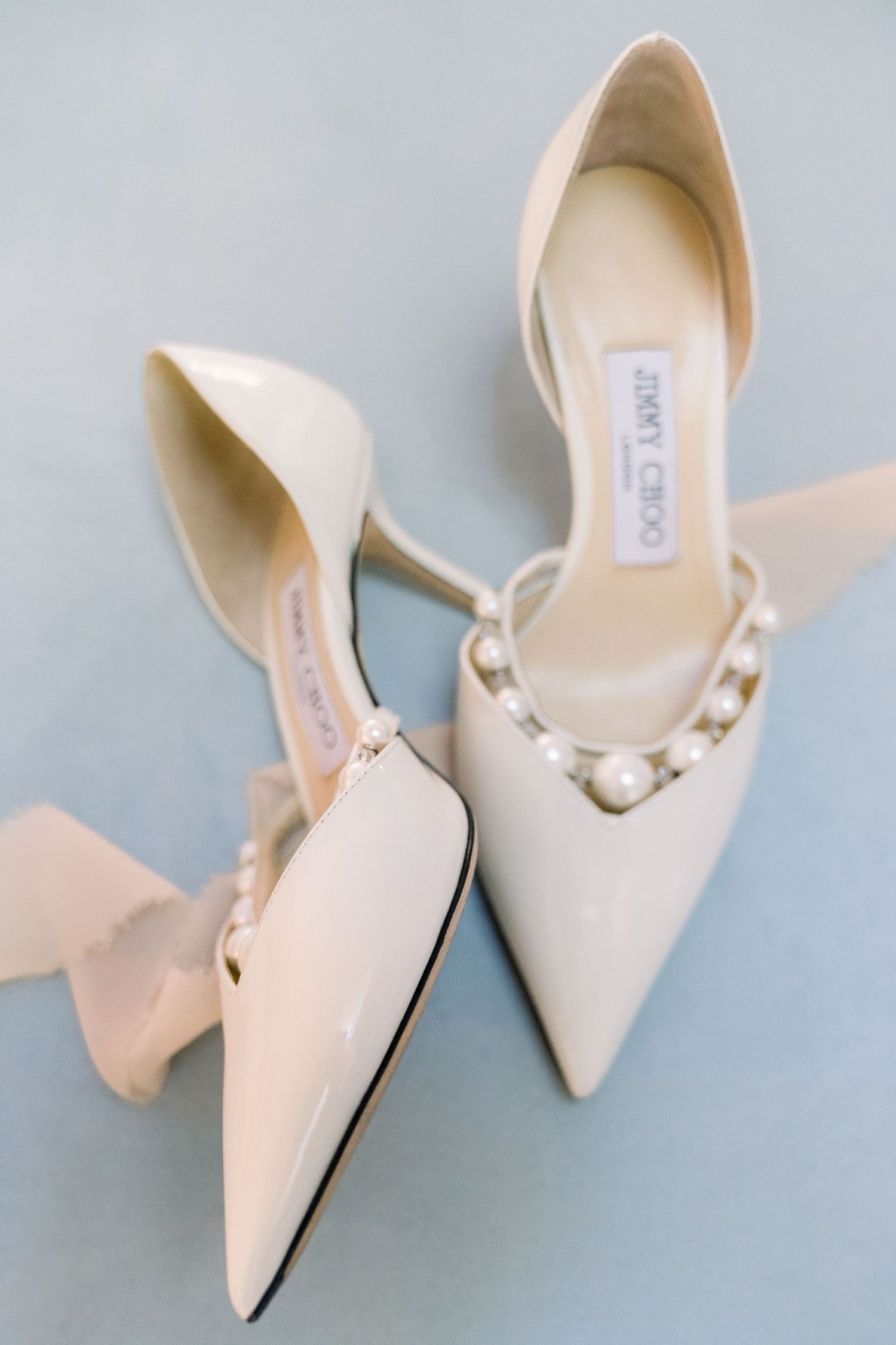 a detail shot of bridal shoes against a blue backdrop