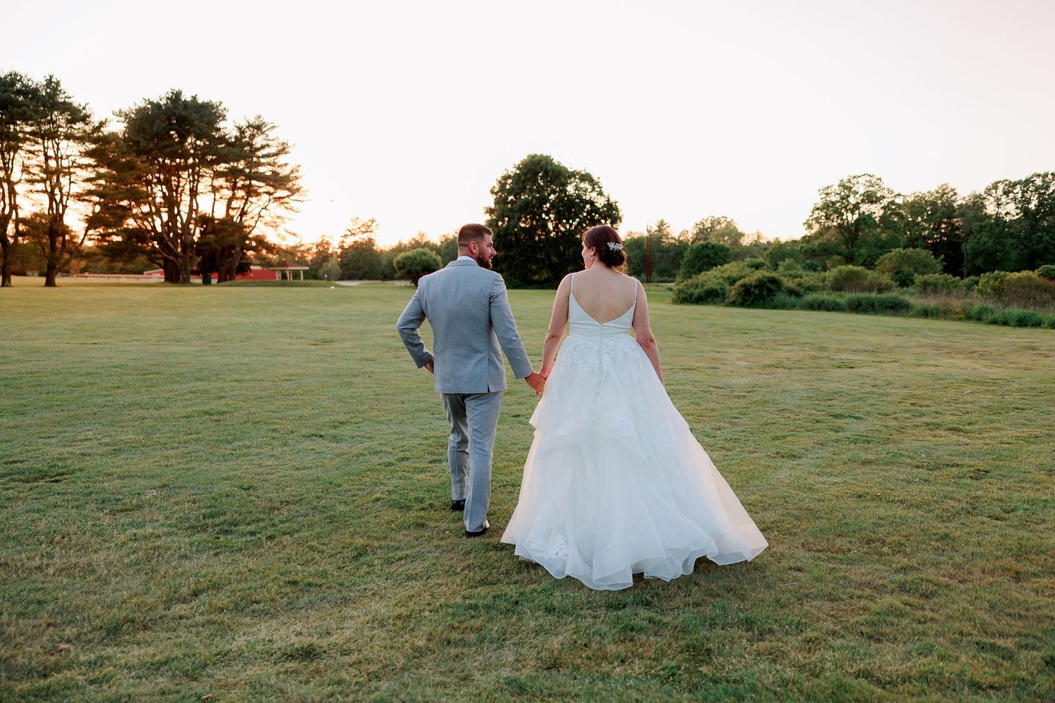a bride and groom walk into the setting sun on a golf course