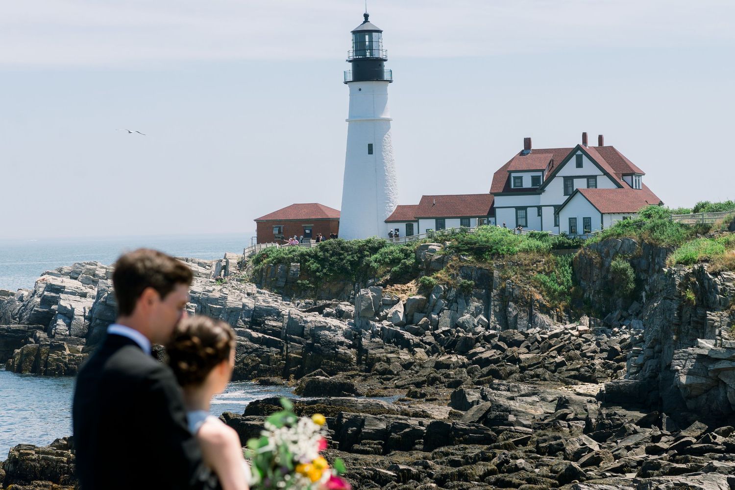 A bride and groom looking at a lighthouse.