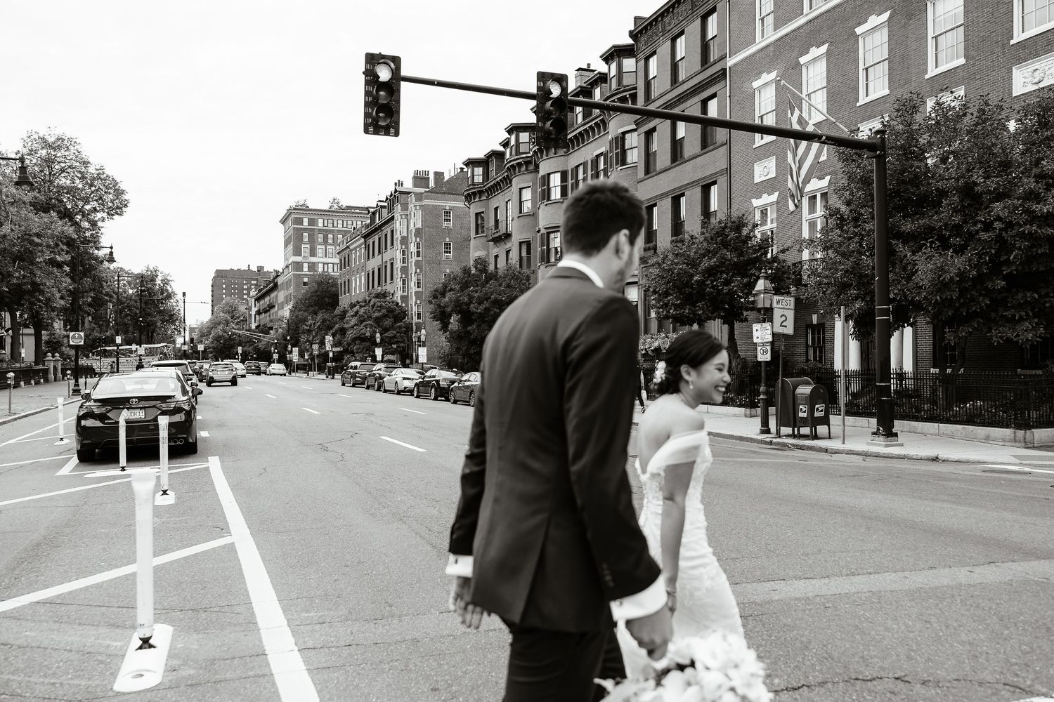 Black and white blurry motion photo of bride and groom crossing a busy street in Boston.