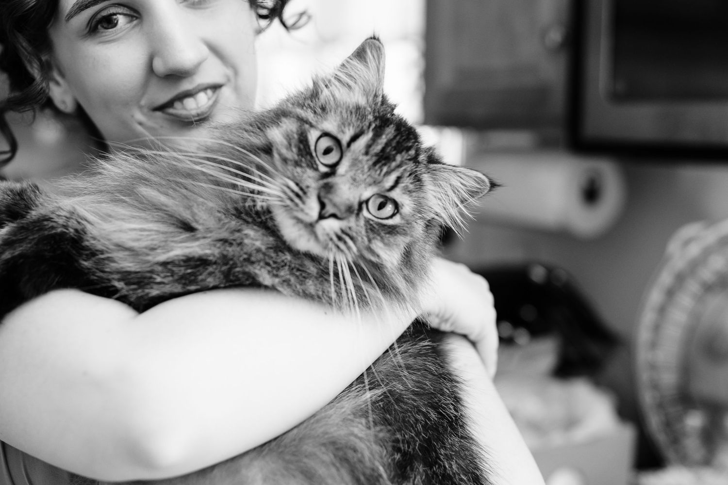 a black and white photo of a wedding party guest holding a cat