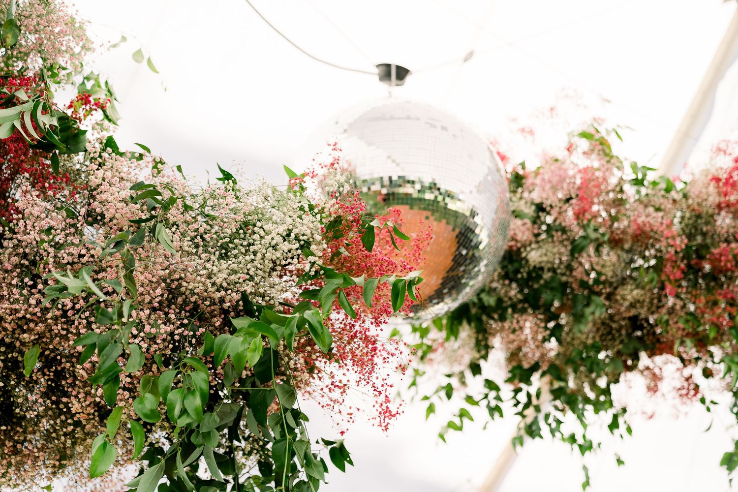 a detail shot of a disco ball surrounded by flowers at a wedding