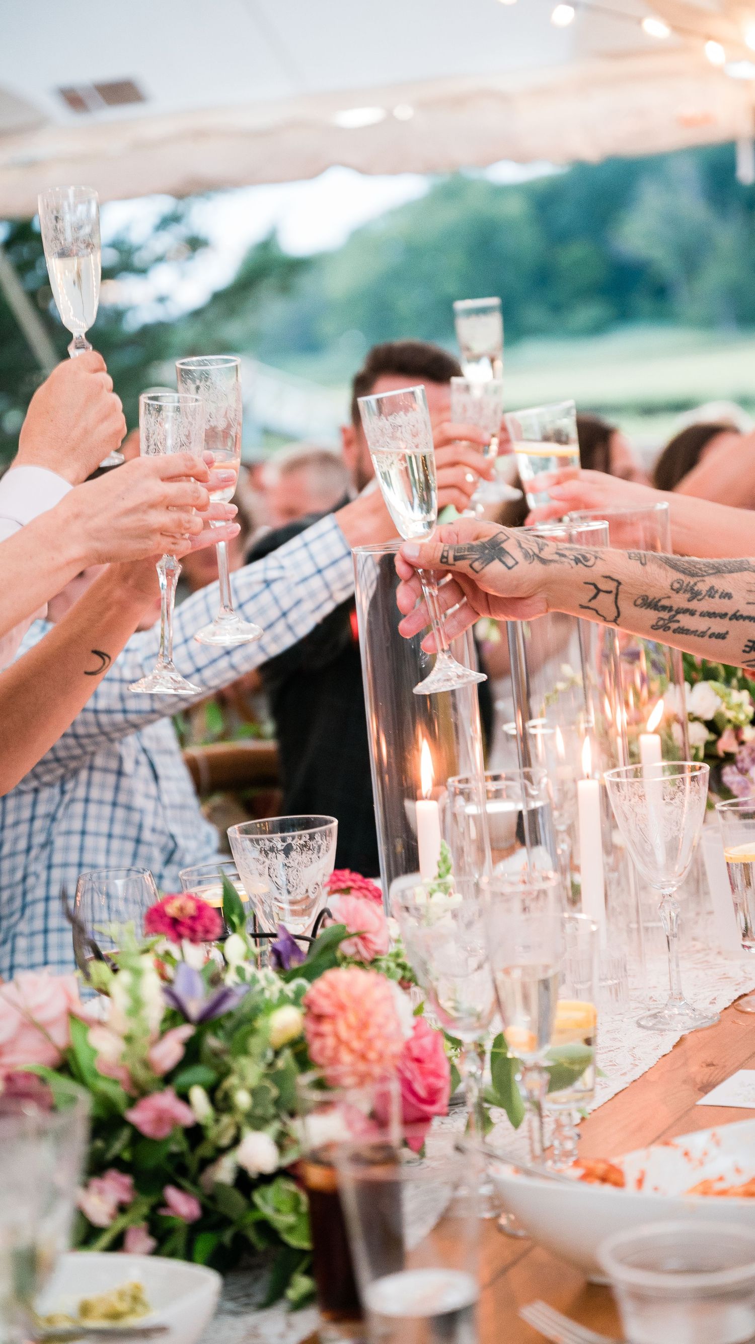 Guests raise their hands during a champagne toast during a garden wedding ceremony.