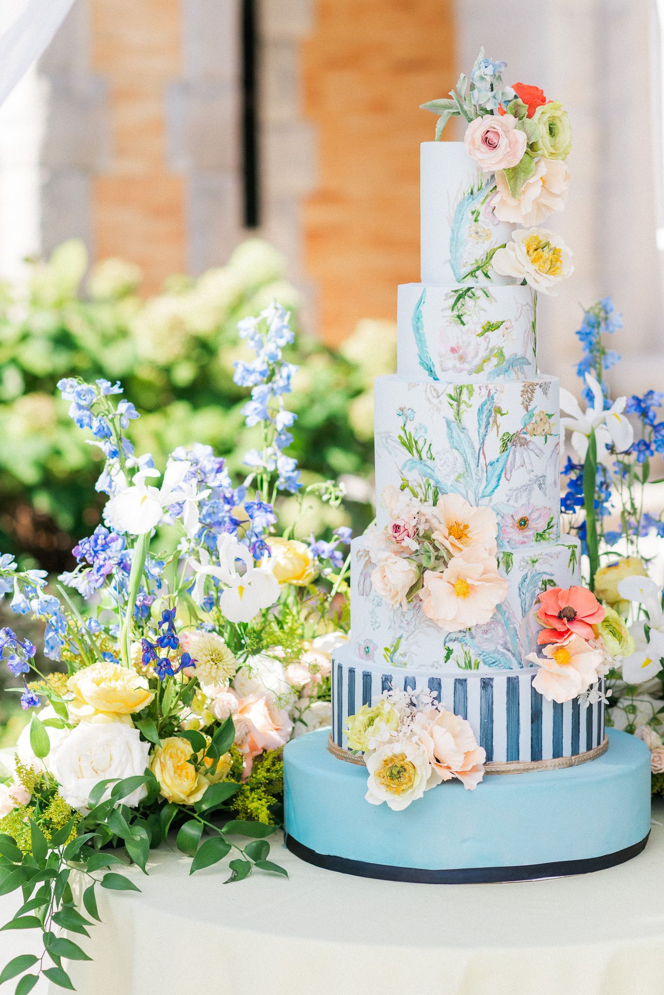 A blue and white wedding cake with fresh flowers.
