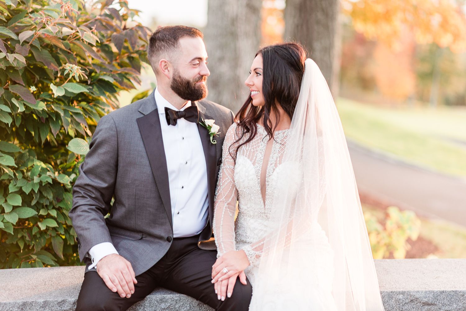 a bride and groom sit and smile at each other during a fall wedding