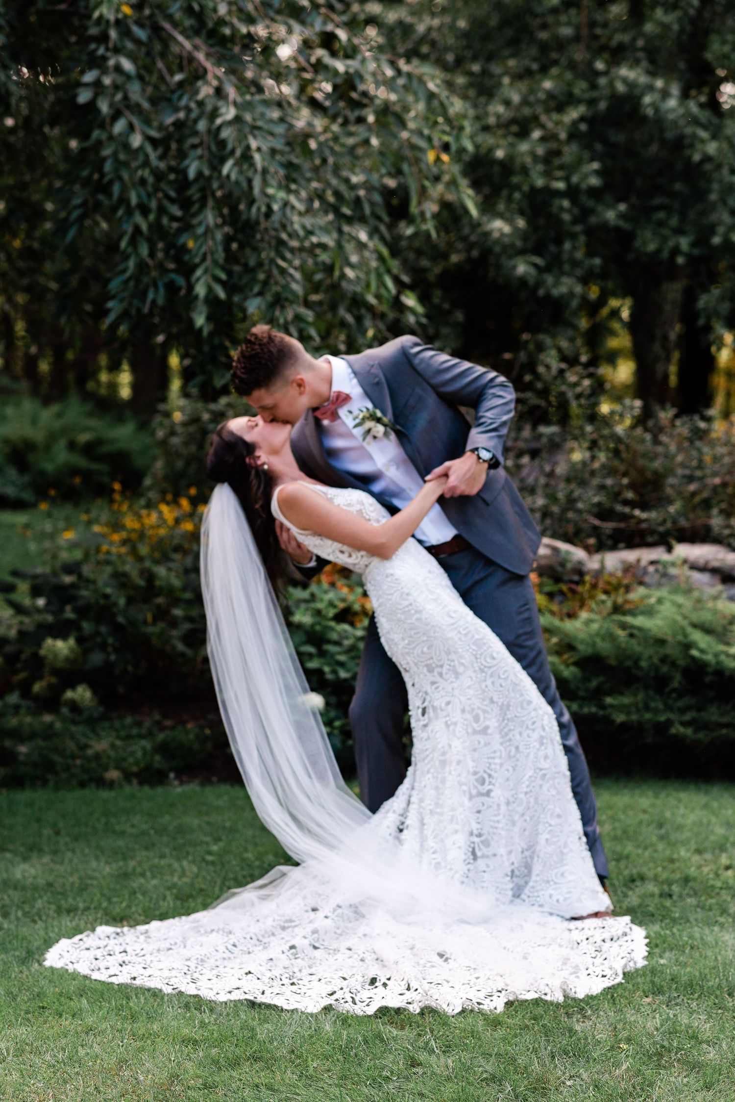 a groom dips a bride for a formal kiss portrait