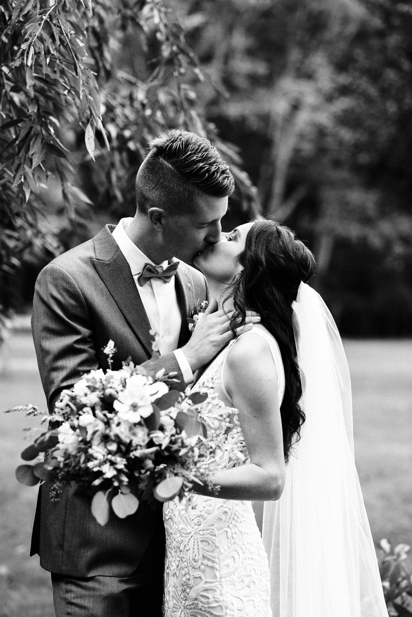 a black and white image of a bride and groom kissing