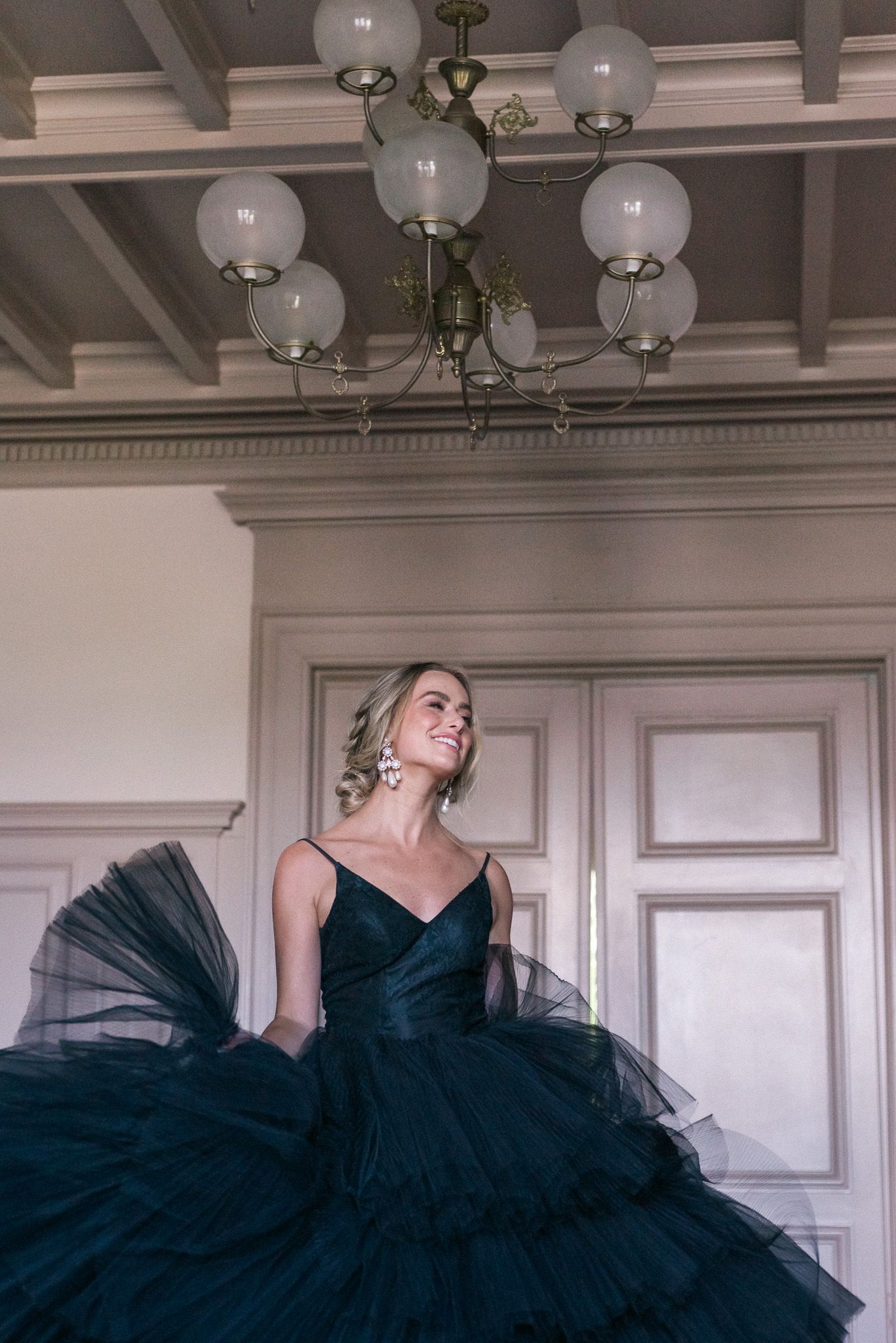 A bride in a black dress twirling and smiling.