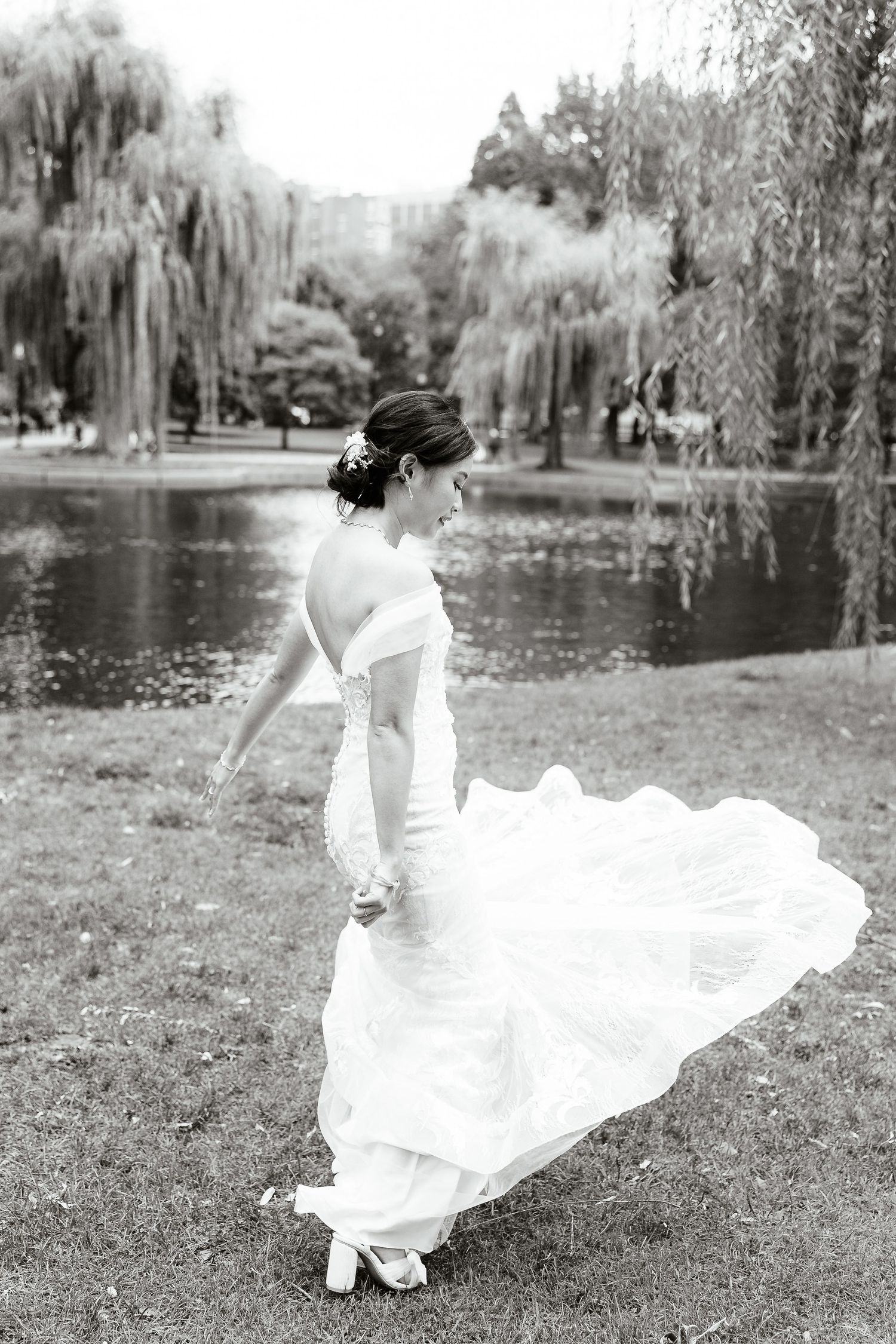 A black and white photo of a bride twirling on the Boston common.