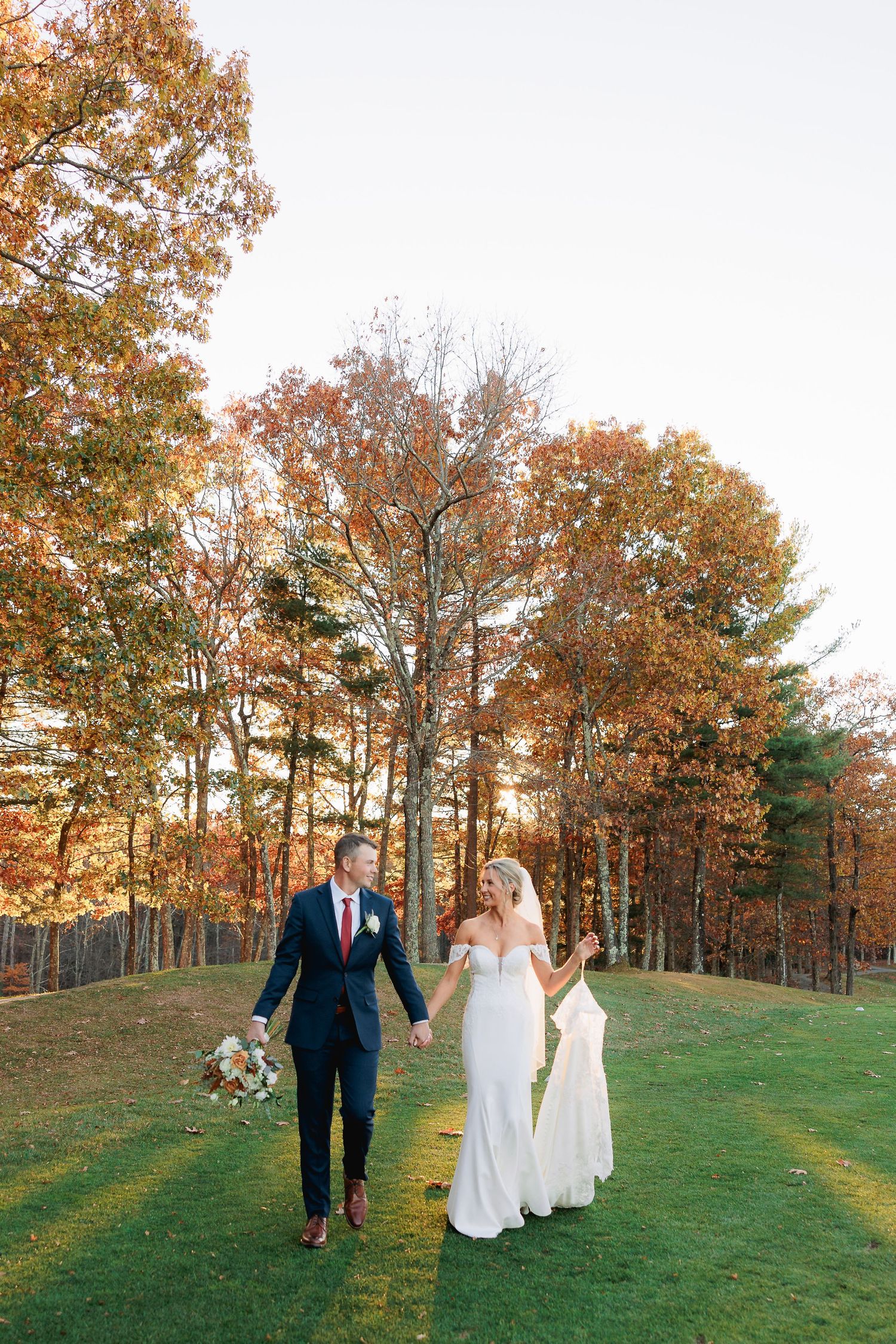 Bride and groom on a golf course at sunset in the fall.