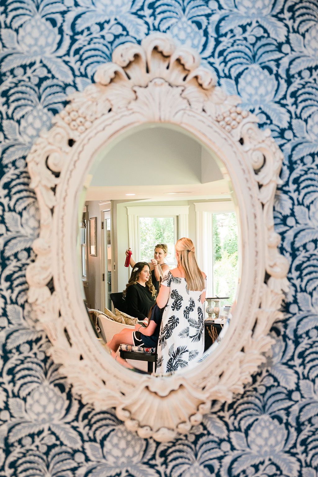 A mirror reflecting an image of a bride getting her hair done before her wedding ceremony.